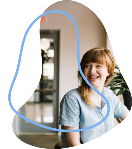 Single employee sat at window looking back across the room, smiling